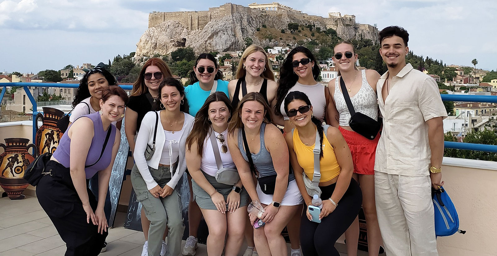 Group of Webster students smiling while standing in front of the Acropolis in Athens, Greece. 